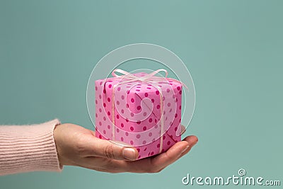 Woman`s hand giving pink gift box in polka dots Stock Photo