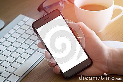 Woman`s hand holding smartphone on desk Stock Photo