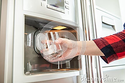 Woman`s hand holds glass and uses refrigerator Stock Photo