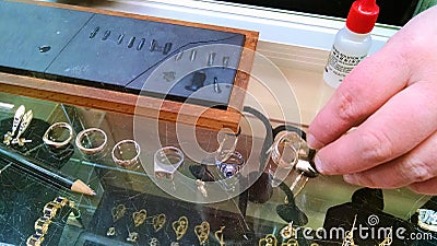 Female metallurgist performs acid tests on jewelry Stock Photo