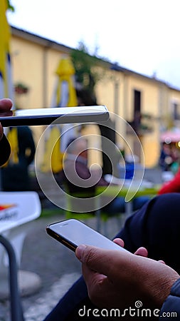 woman's hand with phone checks qrcode, green pass, on man's phone, in open environment Stock Photo