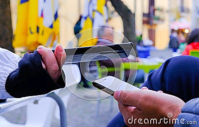 woman's hand with phone checks qrcode, green pass, on man's phone, in open environment Stock Photo