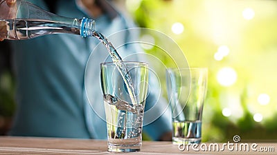 Woman`s hand pouring drinking water from bottle into glass Stock Photo