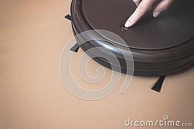 A woman`s hand presses a button Robot Vacuum Cleaner. Close Up. Indoor, housework Stock Photo