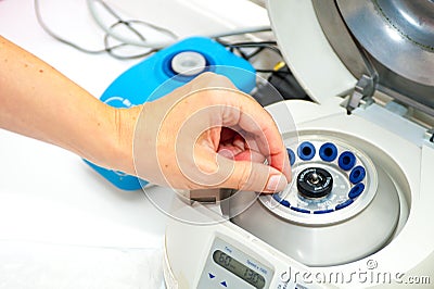 Woman's hand putting small tube into medical centrifuge Stock Photo