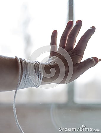 A woman`s hand with a rope that prevents a person from going outside Stock Photo