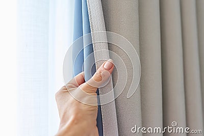 Woman& x27;s hand showing light gray curtain on blue opaque lining, fabric blackout Stock Photo