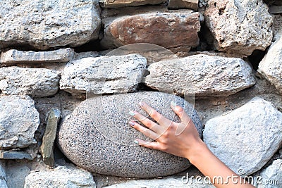 Woman`s hand on a stone wall. Texture of a stone wall. Part of a building wall. Close-up Stock Photo