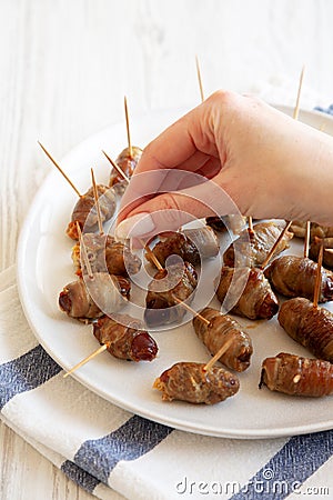 A woman's hand takes Bacon Wrapped Date, side view Stock Photo