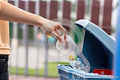 A woman's hand throws a plastic into the recycling container in a park. Ai generated Stock Photo