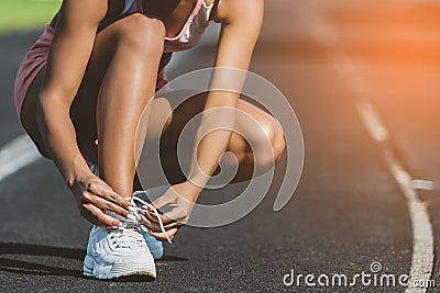 Woman`s hand tying shoe laces at stadium. Preparation for running. Close up. sunshine background Stock Photo