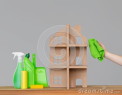 A woman`s hand washes the symbolic house with a green cloth, next to the house - a colourful set of tools for cleaning. Stock Photo