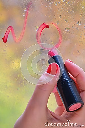 A woman`s hand writes the word No in red lipstick on the glass Stock Photo