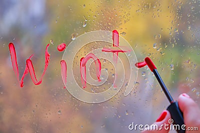 A woman`s hand writes the word Winter in red lipstick on the glass Stock Photo