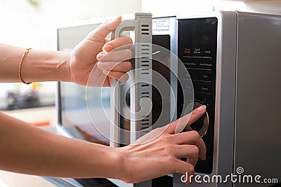 Woman`s Hands Closing Microwave Oven Door And Preparing Food in Stock Photo