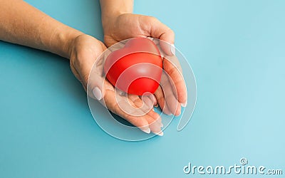 woman's hands hold a heart, blue background. a woman gives her love, an orphanage concept, a gift to mom for a holid Stock Photo