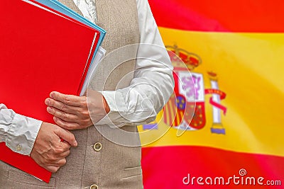 Woman`s hands holding documents against Spain flag background. Education abroad Stock Photo