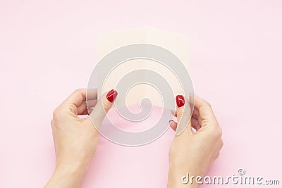Woman`s hands are holding empty mock-up brochure for writing letter above pink background Stock Photo