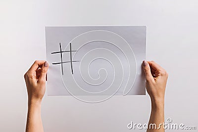 Woman`s hands holding a paper with drawn hashtag symbol and some copy space on it Stock Photo