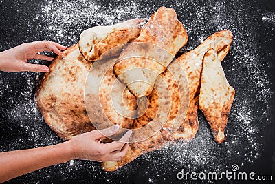 Woman`s hands making a pita bread with flour on dark wooden table Stock Photo