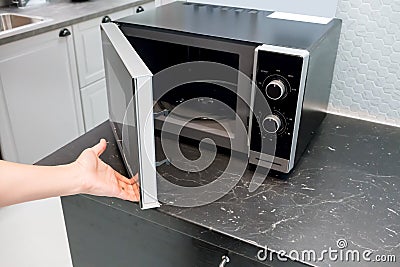 Woman`s Hands open microwave door Stock Photo