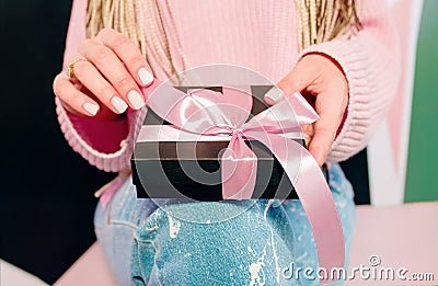 Woman`s hands with pink manicure holding black present box Stock Photo
