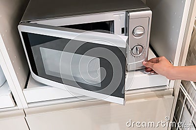 Woman`s Hands pressing button to open microwave door Stock Photo