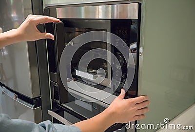 Woman`s Hands pressing button to open microwave door Stock Photo