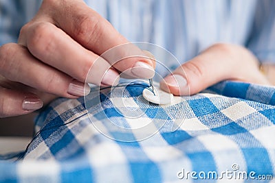 Woman`s hands stitching button on a shirt in tailor shop Stock Photo