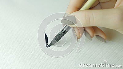 Woman`s hands writing Chinese hieroglyph. Female hand holding a writing brush calligraphy Chinese characters, close up Stock Photo