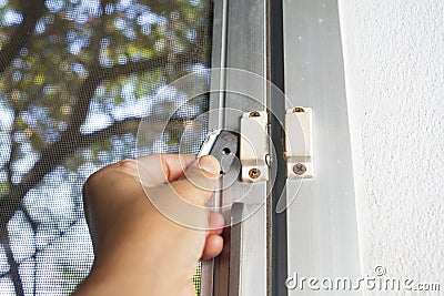 Woman hands holding broken security magnetic lock contact for mosquito wire screen window, Repair Room concept Stock Photo