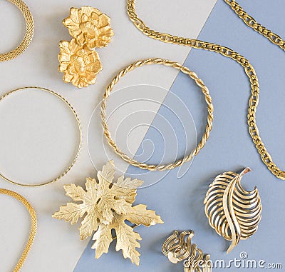 Woman`s Jewelry. Vintage jewelry background. Beautiful gold tone brooches, braceletes, necklaces and earrings on blue background. Stock Photo