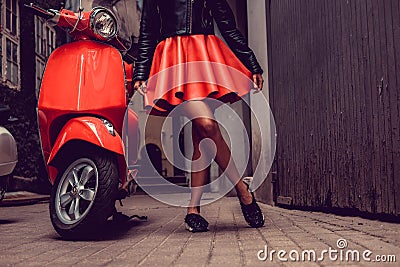 Woman`s legs near red motor scooter. Stock Photo