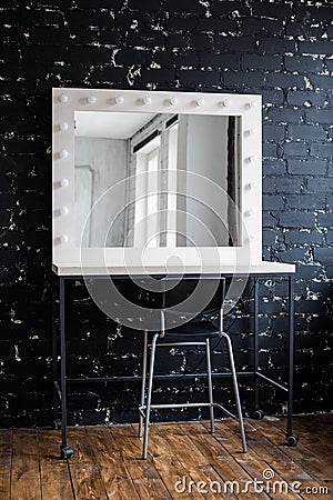 Woman's makeup place with mirror and bulbs at photo studio loft interior black brick wall Stock Photo