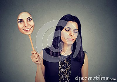 Woman with sad expression taking of a mask expressing cheerfulness Stock Photo