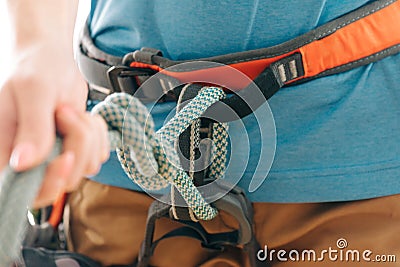 Woman in safety harness holding mountaineering rope knot eight, close-up. Stock Photo