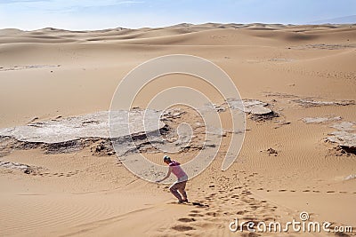 Woman sand boarding on Sahara Desert down the dune, Africa Stock Photo