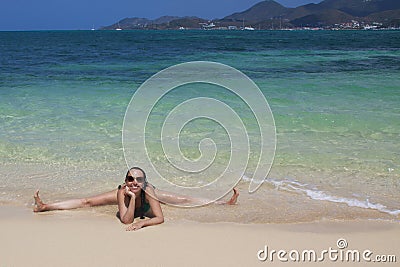 woman on the sand by the sea sits on a twine and laughs Stock Photo