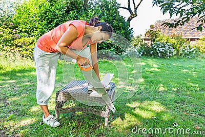 Woman sawing wood outside with handsaw Stock Photo