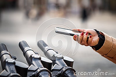 Woman scan QR code by smart phone to unlock and rent electric scooter Stock Photo