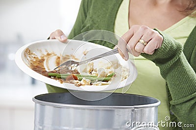 Woman Scraping Food Leftovers Into Garbage Bin Stock Photo