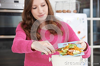 Woman Scraping Vegetable Peelings Into Recycling Bin Stock Photo