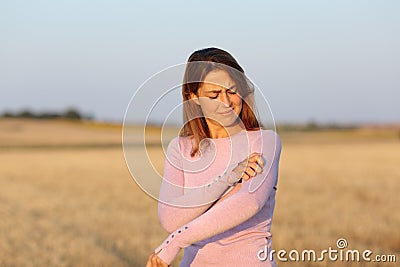 Woman scratching itchy arm in a field Stock Photo