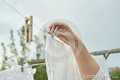 A woman securing her linens on a line with clothespins - an ode to the effectiveness and efficiency of classic laundry Stock Photo