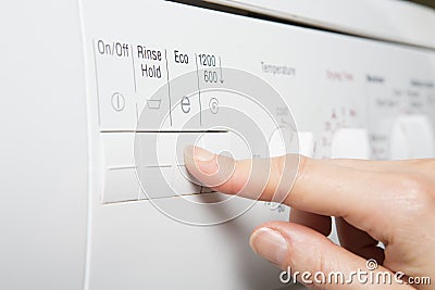 Woman Selecting Economy Program On Washing Machine To Save Energy Stock Photo