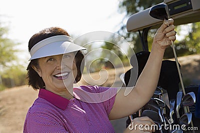 Woman selecting golf club from golf cart Stock Photo