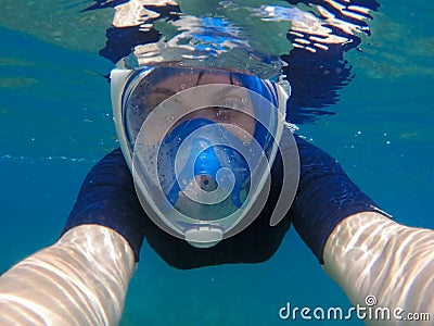 Woman selfie underwater. Young girl swimming under water in modern snorkeling gear. Stock Photo