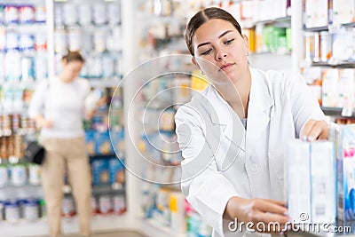 Woman seller puts medical cosmetics and other body care products on shelves Stock Photo