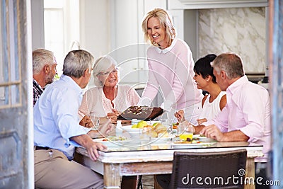 Woman Serving Cake To Group Of Friends Enjoying Meal At Home Stock Photo