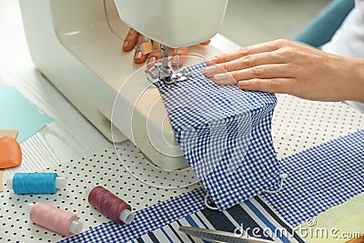 Woman sewing cloth mask with machine at table, closeup. Personal protective equipment during COVID-19 pandemic Stock Photo